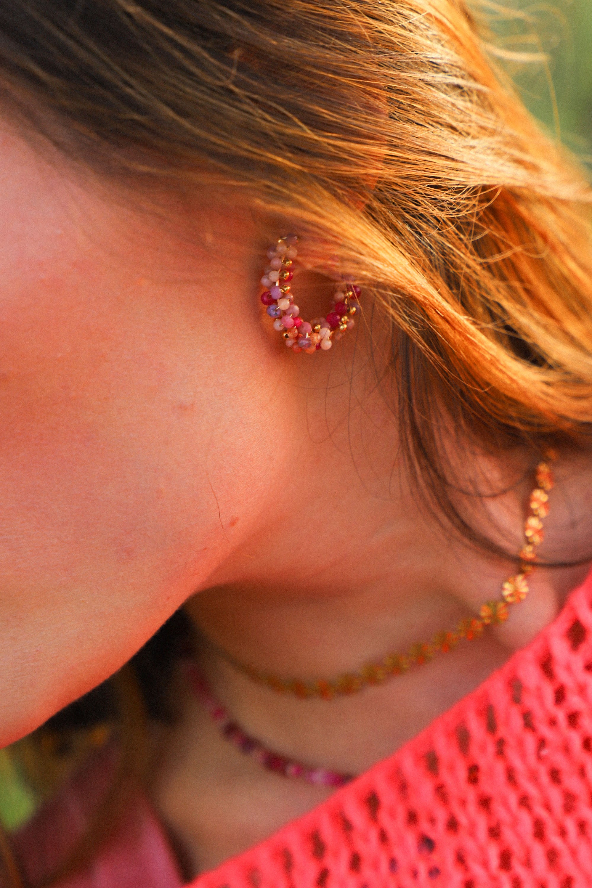 Boucles d'oreilles Jill, ici portées, des créoles moyennes ornées de perles roses tissées.