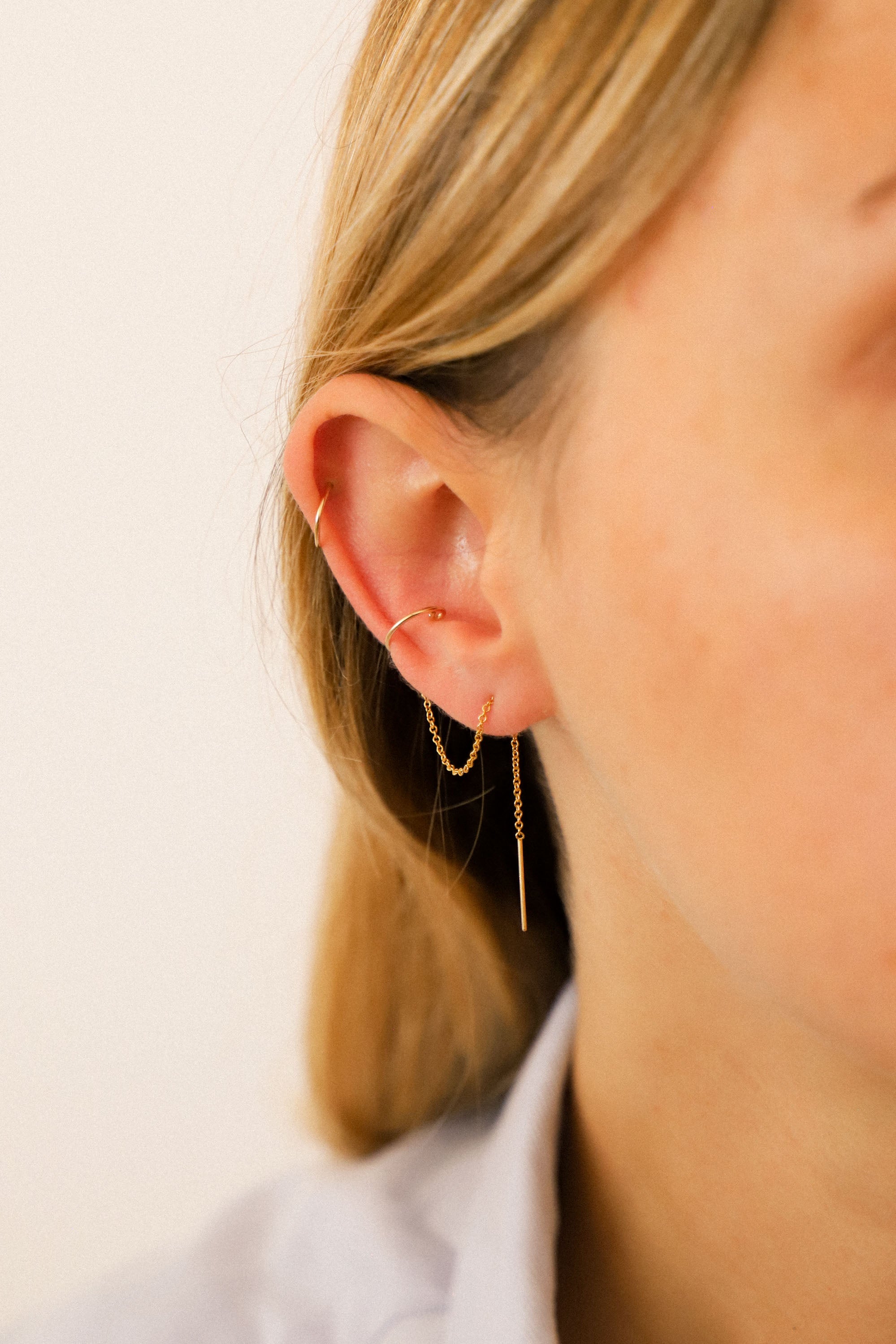 Boucle d'oreille Ella avec chaînette et faux-piercing. Plaqué or 24 carats et faux-piercing en laiton goldfilled.