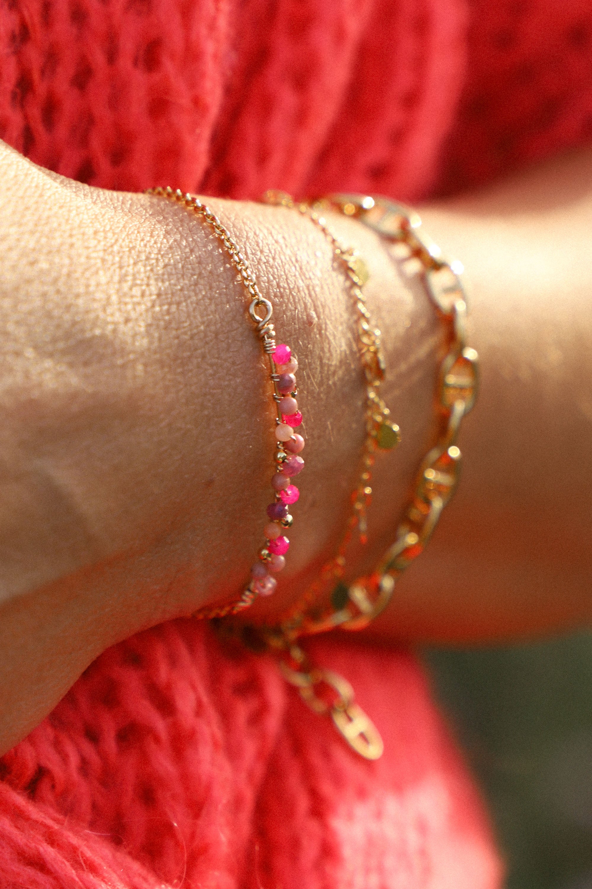 Bracelet Amy, ici porté, composé de perles roses tissées. Le tout, plaqué or 24 carats.