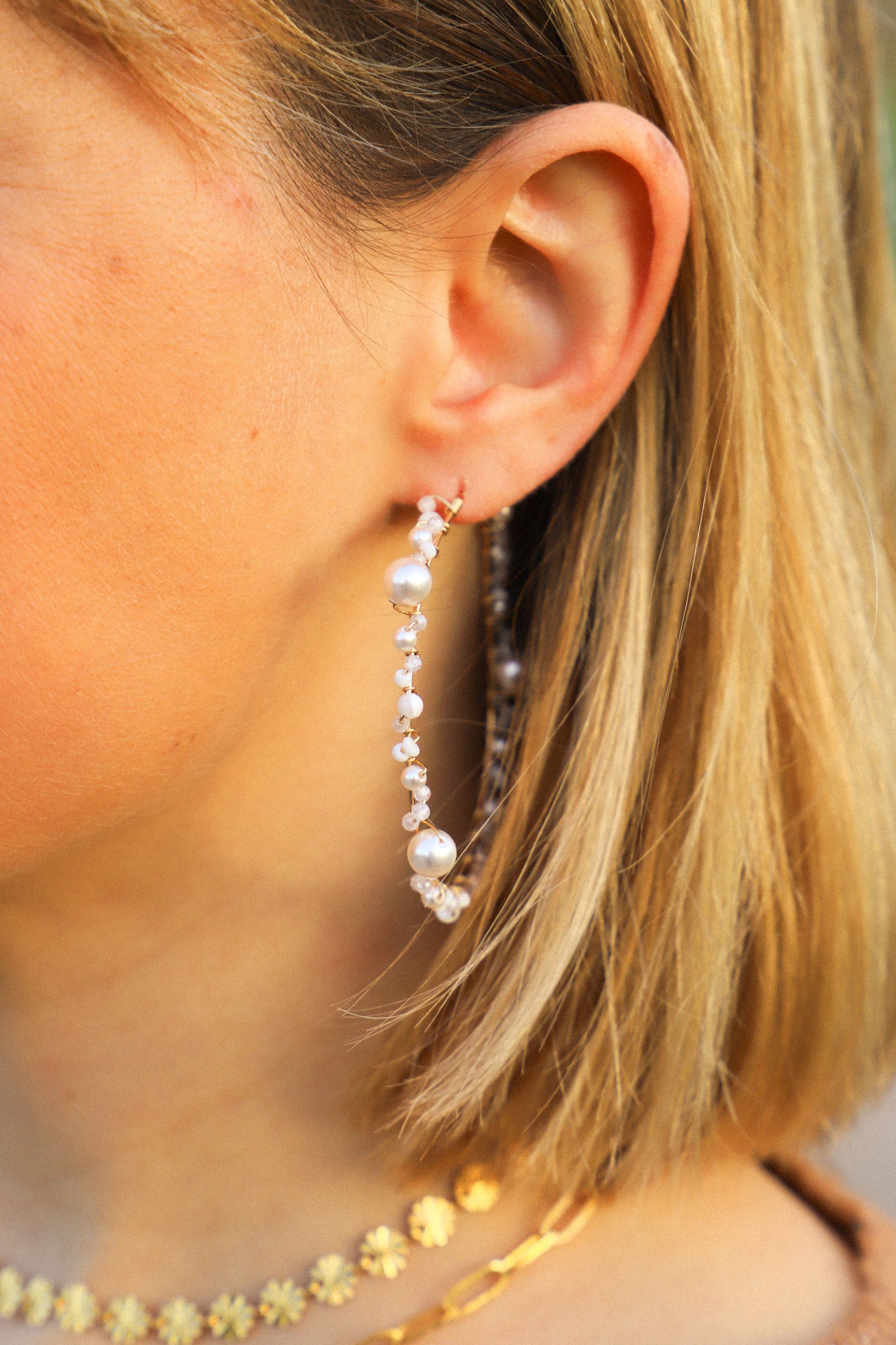 Boucles d'oreilles Jude, de grandes créoles ornées de perles blanches et de nacres.