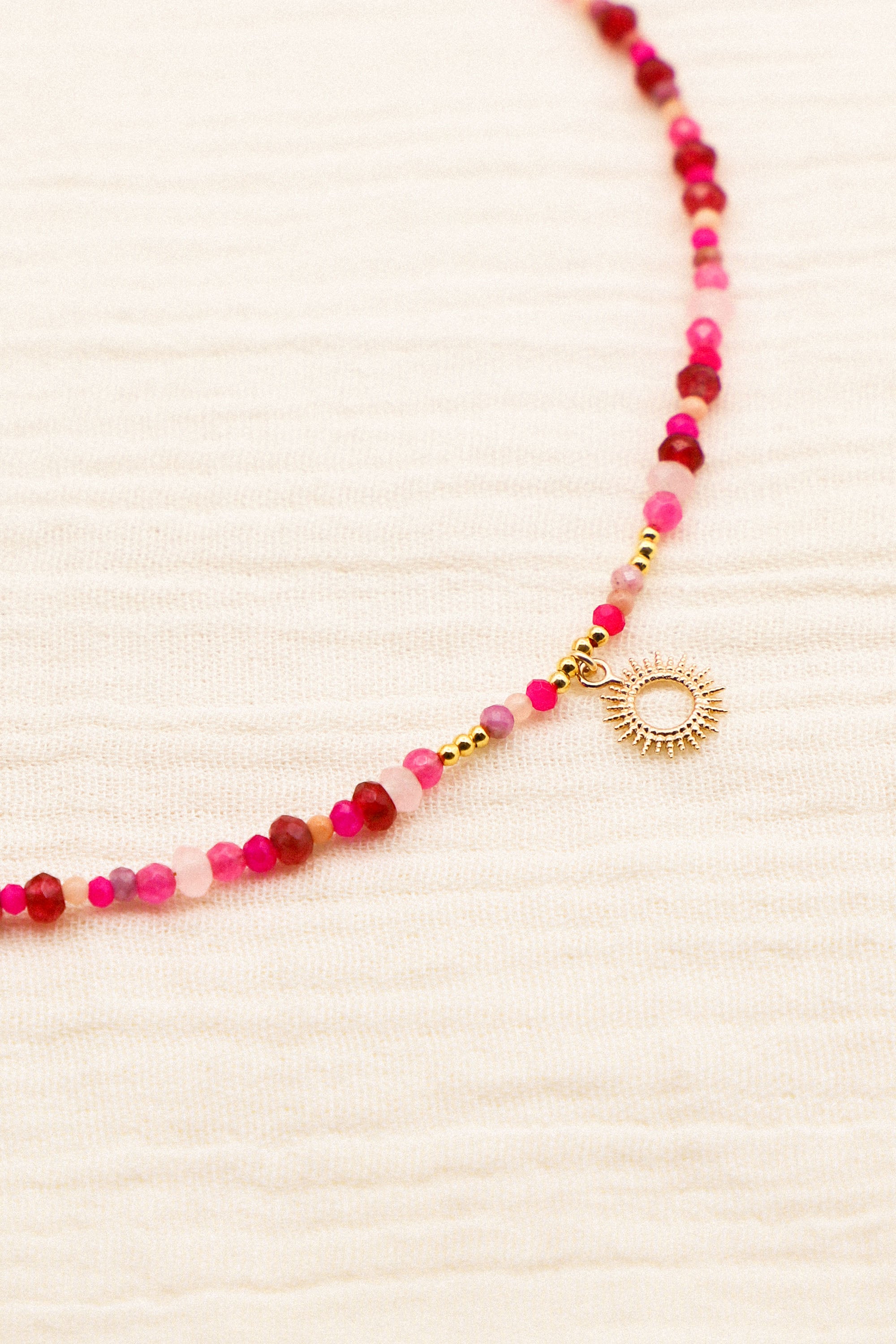 Collier Jane composé de perles roses et d'un petit soleil au centre.